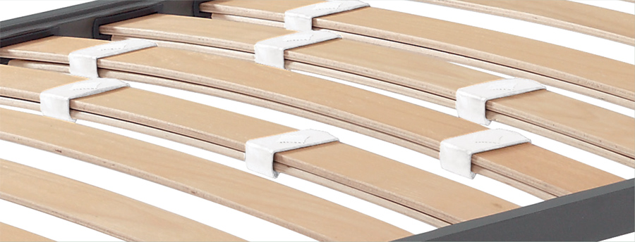 Slatted bed base with stiffness regulators
